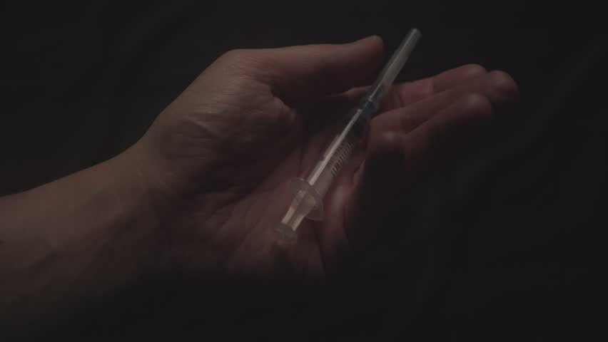 Preparing Syringe for Injection in Low Light. Close-up, shallow dof.