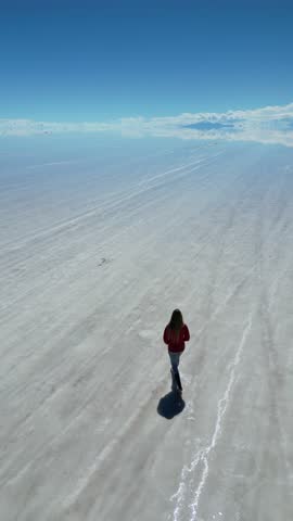Aerial video of a tourist walking in the salt desert of Uyuni, Bolivia