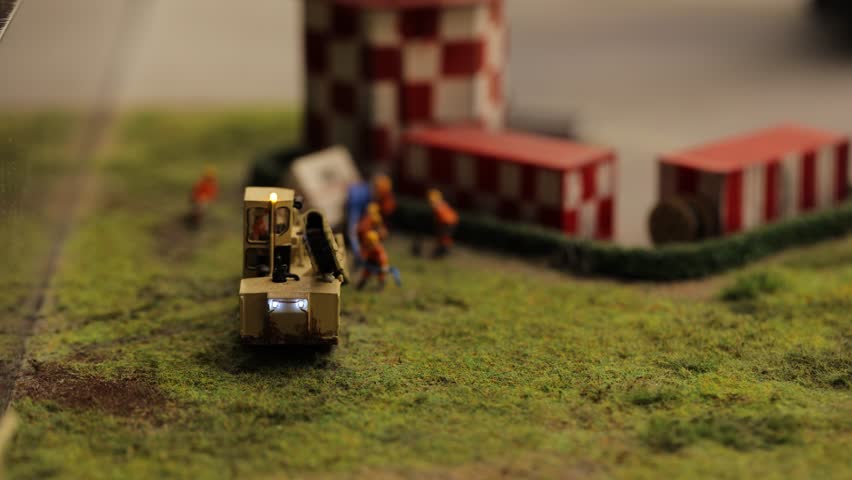 A detailed miniature construction scene featuring machinery and workers in action