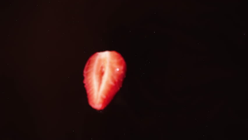 Delicious strawberry falling into chocolate, view from top, super-slow motion, drops flying to sides. Dark chocolate and red berry, cooking tasty sweet dessert for healthy nutrition, organic fruits