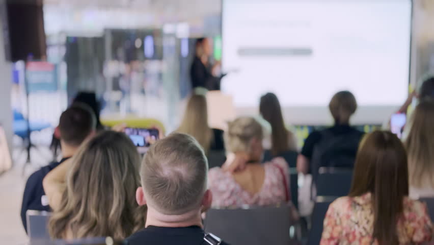 Business audience attentively listening to a presentation in a modern, well-lit office environment. Corporate training, seminars, and professional development concept.