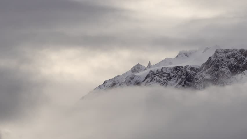 Snow-covered mountain peaks covered by clouds in Patagonia, Argentina. Pan left to right