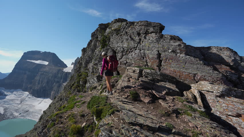 Back View of Female Hiker With Backpack on Viewpoint Above Grinnell Lake in Glacier National Park, Montana USA