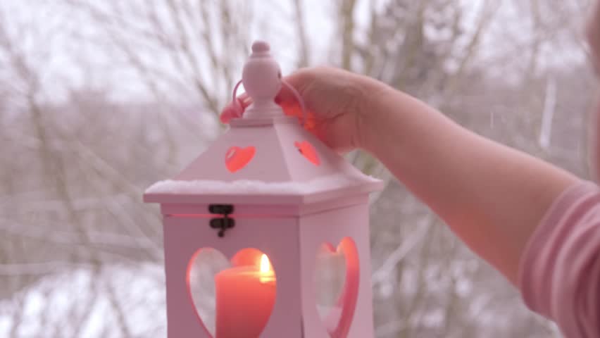 female hand with featuring romantic candle lantern, Christmas atmosphere and festive mood, snowfall in garden, traditional holiday symbols, choosing ingredients for romantic evening in winter season