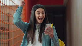 Happy smiling Caucasian student girl smile using mobile phone win smartphone victory winning success female schoolgirl woman pupil teenager teen with schoolbag walk go in school university college - Powered by Shutterstock - Get 15% off with code: PIKWIZARD15