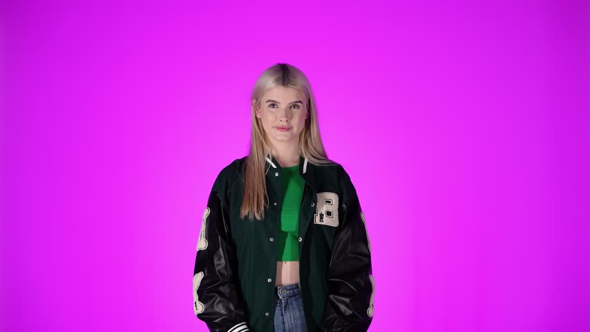Young Blonde Woman Waving Hand, Greeting Gesture Against Purple Color Background, Studio Shot