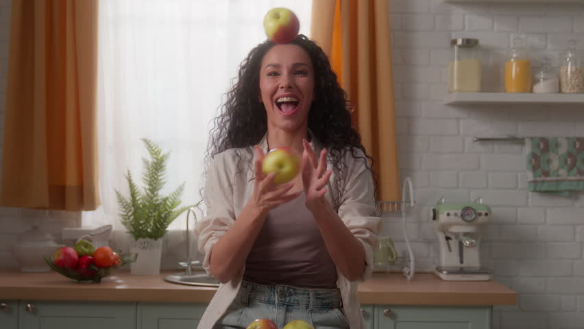 Hispanic Caucasian woman girl female having fun funny play with fruits at kitchen home enjoying joy smiling throw juggle juggling apples throwing laugh diet food delivery vegetarian nutrition health