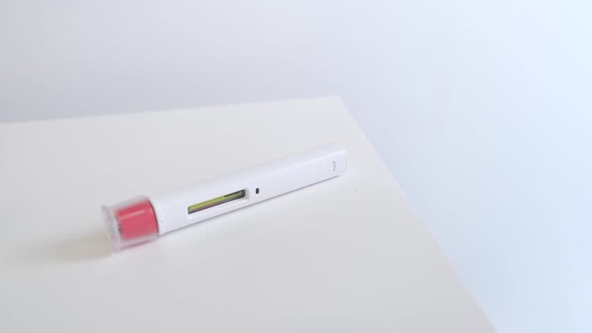 An anonimous person shows clearly and slowly the needle area and the liquid inside a pen injector for biological treatments such as Adalimumab, Etanercept or epinephrine in a didactic way.