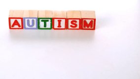 Awareness ribbon falling in front of autism letter blocks in slow motion - Powered by Shutterstock - Get 15% off with code: PIKWIZARD15
