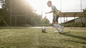 A talented boy is training on the football field. The football player is running with the ball and shooting towards the goal, practicing his kick. - Powered by Shutterstock - Get 15% off with code: PIKWIZARD15
