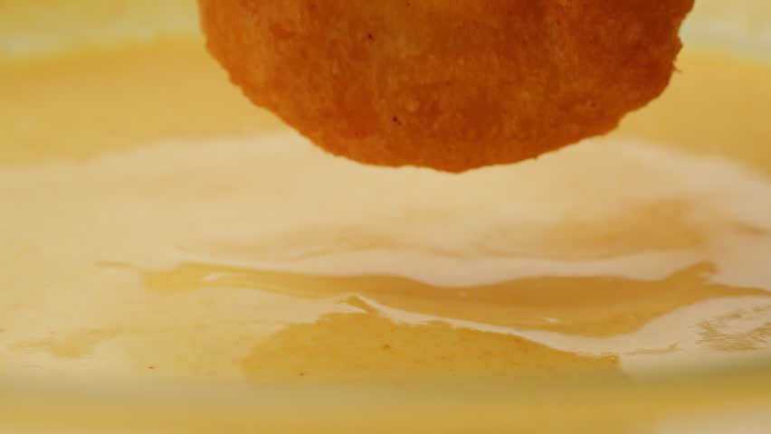 Pouring fry chicken in yellow creamy cheese sauce close-up. Eat chicken nuggets with Peruvian sauce. Fast and junk food concept.