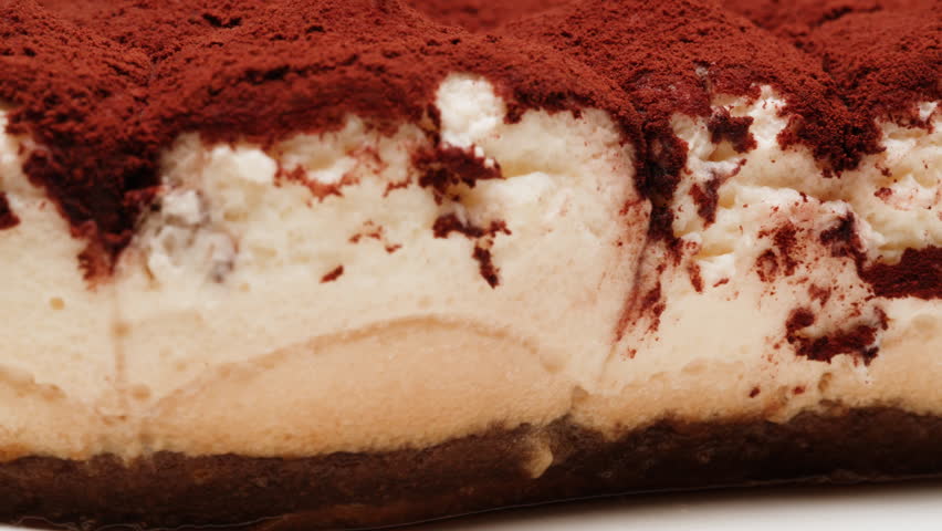 Traditional classic dessert tiramisu on plate close-up. Popular Italian sweet tiramisu made of ladyfinger pastries and dipped in coffee, layered with a whipped mixture of eggs, sugar and mascarpone