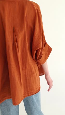 Model girl in orange shirt, black top and blue jeans posing on a white background. Natural clothing style. Fit woman wearing loose clothes