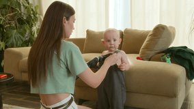 Young mother with prosthetic changes clothes her little son sitting on floor during playing toys in living room. Young woman with prosthesis hand takes care of her baby boy - Powered by Shutterstock - Get 15% off with code: PIKWIZARD15