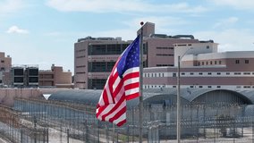 American flag waving in front of high security prison. Jail, inmate, detention center theme. United States judicial system. - Powered by Shutterstock - Get 15% off with code: PIKWIZARD15