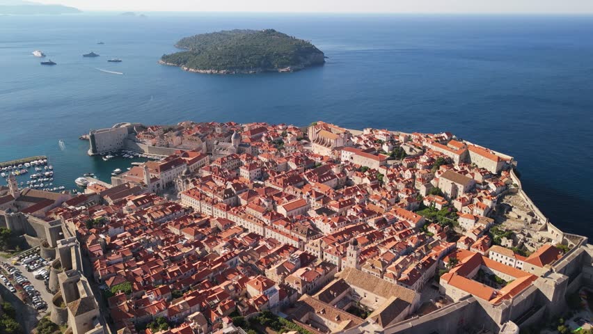 Sunrise flight over old town of Dubrovnik with cinematic pan and glassy water