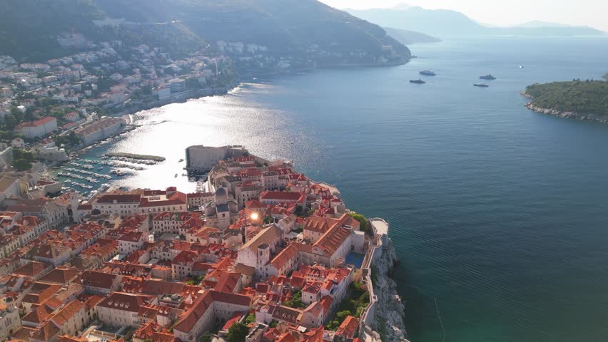 Cinematic aerial drone flight over Dubrovnik, Croatia with old town city walls glistening in the morning sunshine