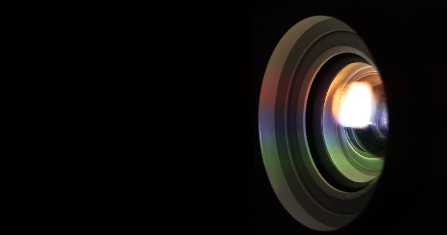 Cinema hall. Projector lens in operation. Movie is shown through projector. Light of different colors passes through lenses