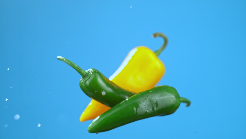 Green and yellow chili bell peppers jumping in air with water droplets, vegetables for cooking. High quality cinematic studio commercial super slow motion 1000fps fresh vegetables moving up and down. - Powered by Shutterstock - Get 15% off with code: PIKWIZARD15