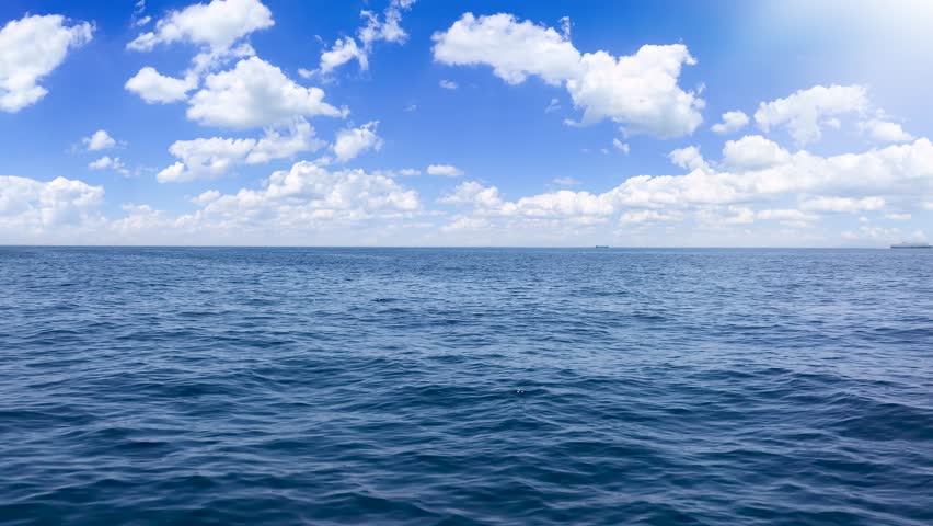 Aerial boat POV flight over the ocean into the endless horizon with sunshine and blue sky