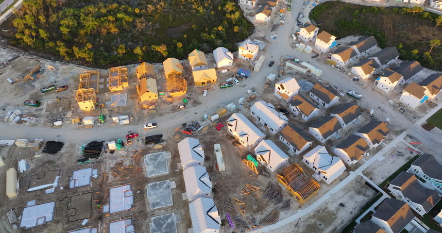 Aerial view of unfinished wooden frames of affordable houses under construction. Development of residential housing in American suburbs. Real estate market in the USA.