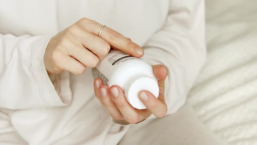 Woman search details about her pills medication. Research reading information about vitamins supplements, side effects or benefits, health care concept.