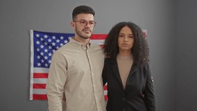 A professional man and woman stand confidently in an office with an american flag in the background, portraying collaboration and patriotism. - Powered by Shutterstock - Get 15% off with code: PIKWIZARD15