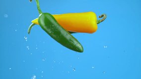 Green and yellow chili bell peppers chilies flying in air with water droplets. High quality cinematic studio commercial super slow motion 1000fps fresh vegetables moving up and down. - Powered by Shutterstock - Get 15% off with code: PIKWIZARD15