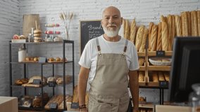Elderly man with a beard holding a tablet in a bakery shop with various types of bread displayed in shelves - Powered by Shutterstock - Get 15% off with code: PIKWIZARD15