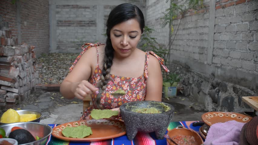 Mexican woman preparing a tostada with guacamole. Mexican food.