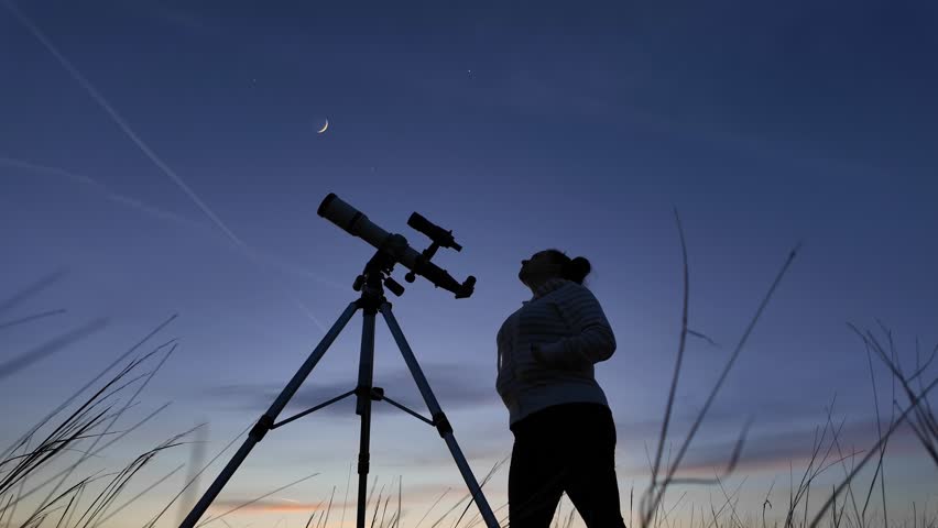Amateur astronomer looking at the evening skies, observing planets, stars, Moon and other celestial objects with a telescope.	
