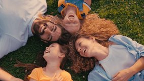 On a sunny day, a happy family lies on the grass, laughing and bonding together, capturing a special moment of joy and togetherness, filled with love and care - Powered by Shutterstock - Get 15% off with code: PIKWIZARD15
