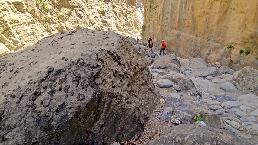 Samaria Gorge, view of the Iron Gates, the most narrow part of the trail with dry riverbed and vertical cliffs, tourists hiking through the gorge, Crete, Greece.
