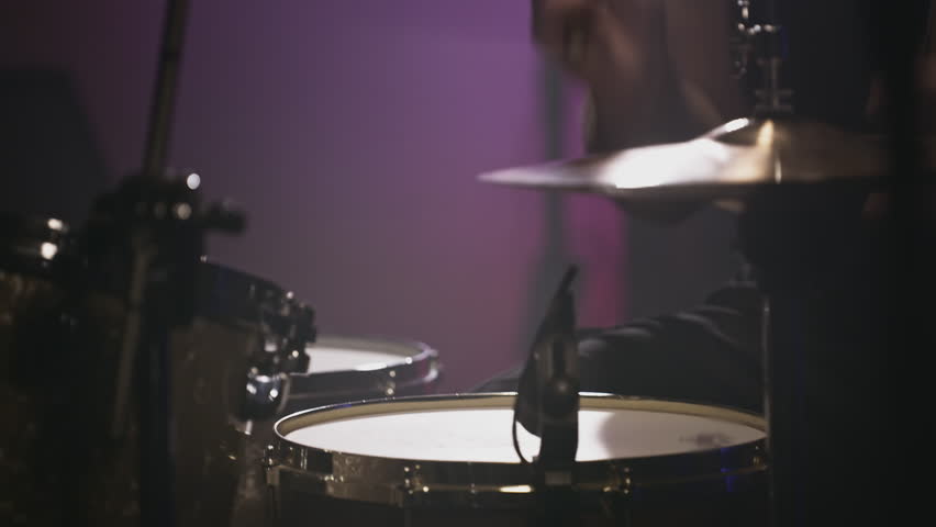 a young attractive guy plays a drum kit. Strikes a cymbal, rehearses. Performance of a rock band, hobby. A man is learning music. Male professional holds drumsticks in hands. Drum set in slow motion