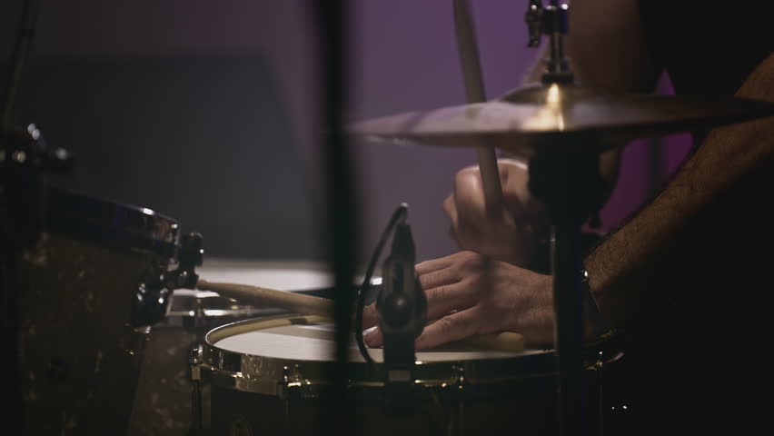 a young attractive guy plays a drum kit. Strikes a cymbal, rehearses. Performance of a rock band, hobby. A man is learning music. Male professional holds drumsticks in hands. Drum set in slow motion