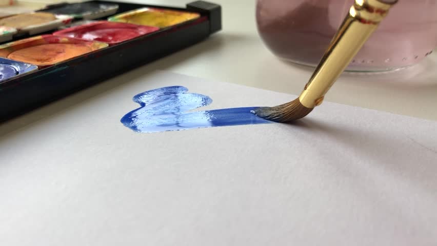 Painting with blue watercolors on a paper with a watercolor brush