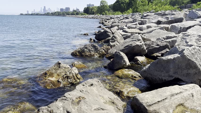 A Tranquil Morning at the Lakeshore in Chicago, Illinois with Skyline in the background with rocks getting splashed.