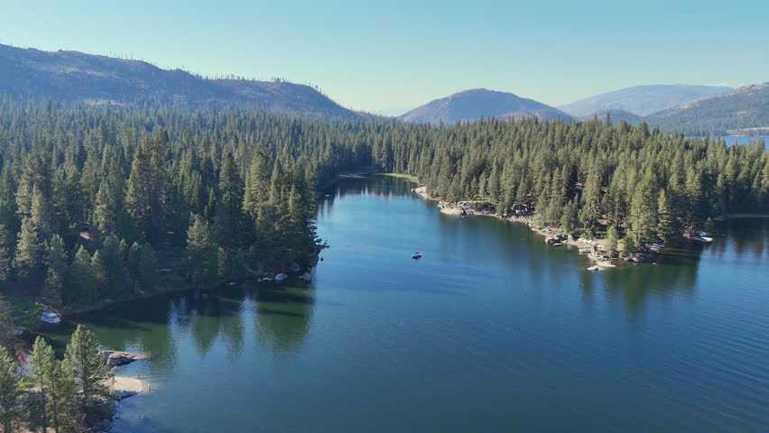 Areal footage of a mountain lake during sunset. The lake is called Shaver Lake located in the California Mountains. The shot pans across the lake from high above it. 