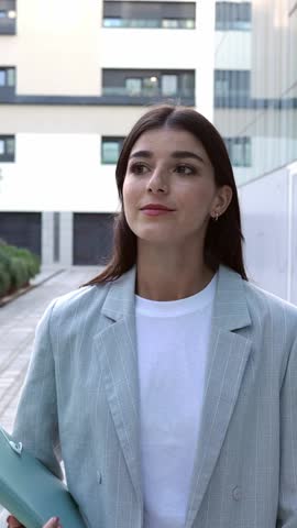 Front view of young adult business woman walking in a office building center. Professional confident empowered female entrepreneur going to work at the office. Vertical HD video. 