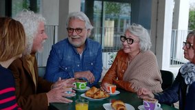 Senior people laughing and enjoying coffee at cafeteria bar. Retired generation community having fun gathered on terrace having breakfast in the morning. Elderly friendship lifestyle concept. - Powered by Shutterstock - Get 15% off with code: PIKWIZARD15