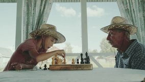 A boy plays chess with his grandfather in chess on the summer veranda in the garden - Powered by Shutterstock - Get 15% off with code: PIKWIZARD15