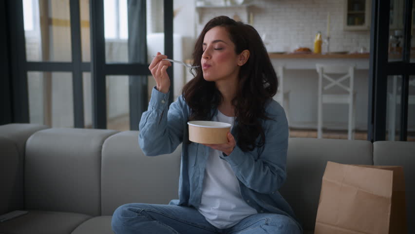 Happy Caucasian hunger girl female enjoy take away order meal lady woman at home sofa couch eating delivery food dish eat cafe restaurant courier service enjoying tasty dancing nutrition diet vegan