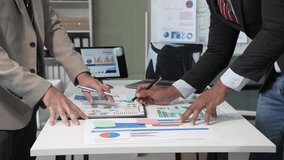 A collaborative meeting at an office desk focusing on teamwork, with discussions centered around financial charts and the sub-account management of work in process in production cost accounting system - Powered by Shutterstock - Get 15% off with code: PIKWIZARD15