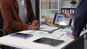 A collaborative meeting at an office desk focusing on teamwork, with discussions centered around financial charts and the sub-account management of work in process in production cost accounting system - Powered by Shutterstock - Get 15% off with code: PIKWIZARD15