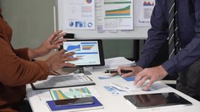 A collaborative meeting at an office desk focusing on teamwork, with discussions centered around financial charts and the sub-account management of work in process in production cost accounting system - Powered by Shutterstock - Get 15% off with code: PIKWIZARD15