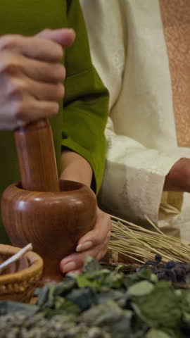 Vertical shot of hands of unrecognizable herbalists preparing and grinding ingredients at alternative medicine apothecary