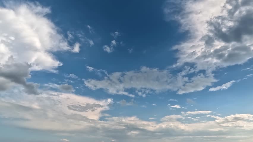 Fluffy clouds in the blue skies mooving left side. 4K video (Ultra High Definition) of cloudscape. Sky and clouds Timelapse. Sun shines through the clouds on the blue sky background.