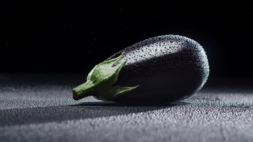 Black eggplant in spray reins on a dark background. High quality 4k footage
