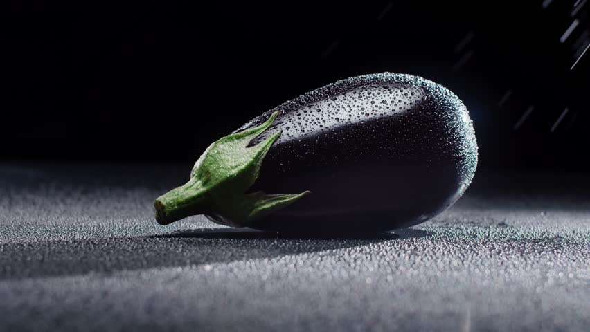 Black eggplant in spray reins on a dark background. High quality 4k footage