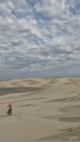 woman walking in the dunes of Lençóis Cidreirenses, in Cidreira, Rio Grande do Sul.  sstkVertical